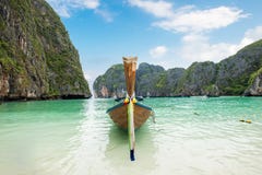 Деревянная шлюпка длинного хвоста поставленная на якорь на mountai seashore и известняка стоковые фотографии rf Деревянная шлюпка длинного хвоста поставленная на якорь на mountai seashore и известняка стоковые фотографии rf