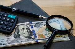 Детали канцелярских принадлежностей: доллар, ручка, калькулятор, увеличитель и блокнот на деревянном столе стоковые изображения rf Детали канцелярских принадлежностей: доллар, ручка, калькулятор, увеличитель и блокнот на деревянном столе стоковые изображения rf