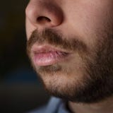 Деталь поврежденных губ молодого человека с бородой стоковая фотография Деталь поврежденных губ молодого человека с бородой стоковая фотография