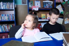 Дети в библиотеке читая интересную книгу Учить маленькой девочки и мальчика стоковые изображения rf Дети в библиотеке читая интересную книгу Учить маленькой девочки и мальчика стоковые изображения rf