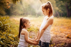 Детство, семья, приятельство и концепция людей - 2 счастливых сестры детей обнимая outdoors стоковое изображение rf Детство, семья, приятельство и концепция людей - 2 счастливых сестры детей обнимая outdoors стоковое изображение rf