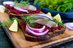 Диетические сандвичи с свеклами, куски посоленных сельдей и красный лук на хлебе рож на черной предпосылке Стоковые Фотографии RF Диетические сандвичи с свеклами, куски посоленных сельдей и красный лук на хлебе рож на черной предпосылке Стоковые Фотографии RF