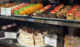 Дисплей окна магазина печенья с разнообразием пирожных, булочек, macaroons, тортов стоковые фотографии rf Дисплей окна магазина печенья с разнообразием пирожных, булочек, macaroons, тортов стоковые фотографии rf
