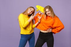 2 довольно молодых белокурых девушки сестер близнецов в ярких одеждах указывая указательный палец, держа желтый скейтборд изолиро стоковая фотография 2 довольно молодых белокурых девушки сестер близнецов в ярких одеждах указывая указательный палец, держа желтый скейтборд изолиро стоковая фотография