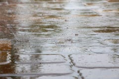 Дождевые капли Splattering на плитках палубы бассейна Стоковое Изображение Дождевые капли Splattering на плитках палубы бассейна Стоковое Изображение