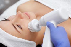 Доктор-cosmetologist делает прибором процедуру чистки стороны оборудования с мягкой вращая щеткой стоковое фото rf Доктор-cosmetologist делает прибором процедуру чистки стороны оборудования с мягкой вращая щеткой стоковое фото rf