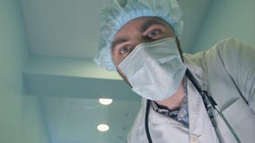 Доктор в маске смотря вниз на пациенте проверяя его сознавание стоковое изображение rf Доктор в маске смотря вниз на пациенте проверяя его сознавание стоковое изображение rf