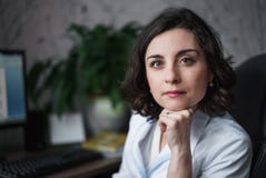 Доктор женщины с внимательным серьезным взглядом в белой медицинской робе сидя на таблице На книгах таблицы, мониторе компьютера стоковые изображения Доктор женщины с внимательным серьезным взглядом в белой медицинской робе сидя на таблице На книгах таблицы, мониторе компьютера стоковые изображения