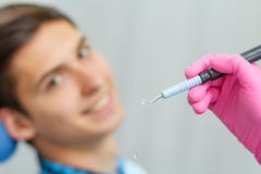 Доктор нося розовые перчатки держит ультразвуковую зубоврачебную пересчетку w стоковое фото Доктор нося розовые перчатки держит ультразвуковую зубоврачебную пересчетку w стоковое фото