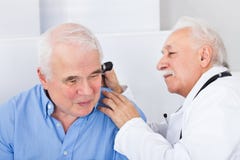 Доктор рассматривая ухо старшего человека с otoscope стоковое фото rf Доктор рассматривая ухо старшего человека с otoscope стоковое фото rf
