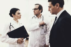 Доктор с стетоскопом принимает взятку от успешного бизнесмена, смотря вокруг breton стоковое изображение rf Доктор с стетоскопом принимает взятку от успешного бизнесмена, смотря вокруг breton стоковое изображение rf