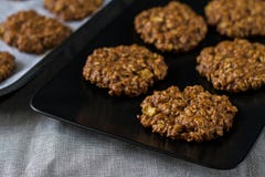 Домодельные золотые печенья овсяной каши с яблоком и гайки на черной плите стоковая фотография rf Домодельные золотые печенья овсяной каши с яблоком и гайки на черной плите стоковая фотография rf