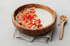 Домодельный югурт в деревянном шаре с клубникой и granola или muesli на светлой таблице, здоровом завтраке стоковое изображение rf Домодельный югурт в деревянном шаре с клубникой и granola или muesli на светлой таблице, здоровом завтраке стоковое изображение rf
