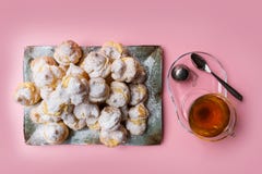 Домодельные profiteroles служили на плите с чашкой чаю на розовой предпосылке Плоское положение стоковая фотография rf Домодельные profiteroles служили на плите с чашкой чаю на розовой предпосылке Плоское положение стоковая фотография rf