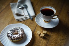 Донут взбрызнутый с обломоками шоколада, чашка черного чая, linen салфетка, сахар соединяет на деревянном столе кафе уютное стоковые фото Донут взбрызнутый с обломоками шоколада, чашка черного чая, linen салфетка, сахар соединяет на деревянном столе кафе уютное стоковые фото