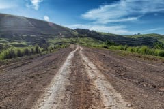 Дорога грязи с метками автошины бежит через зеленую долину в Malanje anisette вышесказанного стоковое изображение Дорога грязи с метками автошины бежит через зеленую долину в Malanje anisette вышесказанного стоковое изображение
