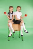 2 девушки в школьной форме сидя на столе и едят яблока Стоковая Фотография RF