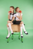 2 девушки в школьной форме сидя на столе и едят яблока Стоковые Изображения