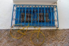 Желтая ржавая смертная казнь через повешение велосипеда на голубом окне с железной решеткой стоковые фотографии rf Желтая ржавая смертная казнь через повешение велосипеда на голубом окне с железной решеткой стоковые фотографии rf