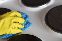 Женская рука в желтой перчатке моет электрическую плиту с ветошью стоковые фотографии rf Женская рука в желтой перчатке моет электрическую плиту с ветошью стоковые фотографии rf