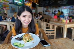 Женская рука держа meal плиты жареных рисов на таблице в ресторане с людьми толпы в предпосылке молодая азиатская еда женщины та стоковое фото rf Женская рука держа meal плиты жареных рисов на таблице в ресторане с людьми толпы в предпосылке молодая азиатская еда женщины та стоковое фото rf