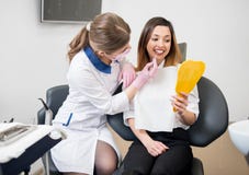 Женские пациент и дантист с зондом проверяют зубы на зеркале после зубоврачебной обработки в зубоврачебном офисе зубоврачевание стоковое фото rf Женские пациент и дантист с зондом проверяют зубы на зеркале после зубоврачебной обработки в зубоврачебном офисе зубоврачевание стоковое фото rf