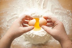Женские руки ломая яйцо цыпленка в муку стоковые фото Женские руки ломая яйцо цыпленка в муку стоковые фото