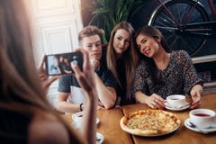 Женские руки принимая фото с smartphone молодых жизнерадостных друзей стоковое изображение Женские руки принимая фото с smartphone молодых жизнерадостных друзей стоковое изображение