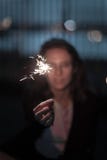 Женский в нерезкости держа яркую ручку искры вечером стоковые фотографии rf Женский в нерезкости держа яркую ручку искры вечером стоковые фотографии rf