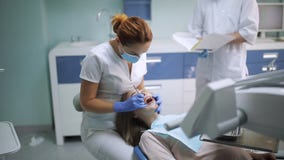 Женский дантист проверяя терпеливые зубы девушки дантист с зеркалом проверяя терпеливые зубы девушки вверх на зубоврачебном офисе сток-видео Женский дантист проверяя терпеливые зубы девушки дантист с зеркалом проверяя терпеливые зубы девушки вверх на зубоврачебном офисе сток-видео