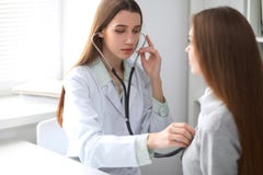 Женский доктор рассматривая ее пациента с стетоскопом пока сидящ на таблице около окна в больнице врач Стоковые Фото Женский доктор рассматривая ее пациента с стетоскопом пока сидящ на таблице около окна в больнице врач Стоковые Фото