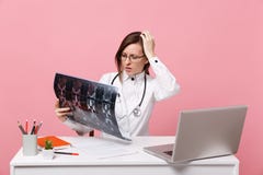 Женский доктор сидит на работе стола на компьютере с медицинским рентгеновским снимком владением документа в изолированной больни стоковые фотографии rf Женский доктор сидит на работе стола на компьютере с медицинским рентгеновским снимком владением документа в изолированной больни стоковые фотографии rf