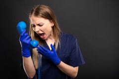 Женский носить доктора scrubs выкрикивать на приемнике телефона стоковое изображение Женский носить доктора scrubs выкрикивать на приемнике телефона стоковое изображение
