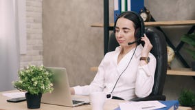Женский работник центра телефонного обслуживания отвечает звонку клиента в офисе Женский работник центра телефонного обслуживания отвечает звонку клиента в офисе