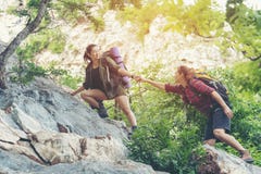 Женщина Hiker группы помогая ее другу взбирается вверх последний раздел захода солнца в горах Сыгранность путешественника идя в в стоковые изображения rf Женщина Hiker группы помогая ее другу взбирается вверх последний раздел захода солнца в горах Сыгранность путешественника идя в в стоковые изображения rf