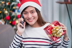 Женщина Азии носит шляпу santa и подарочная коробка удержания и использует мобильные животики стоковые фото Женщина Азии носит шляпу santa и подарочная коробка удержания и использует мобильные животики стоковые фото