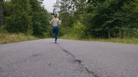 Женщина бегуна бежать на дороге в лесе в slowmotion фитнес outdoors Съемка с steadicam Концепция утра идущая видеоматериал Женщина бегуна бежать на дороге в лесе в slowmotion фитнес outdoors Съемка с steadicam Концепция утра идущая видеоматериал