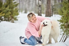 Женщина в лесе зимы идя с собакой Снежок падает стоковое фото rf Женщина в лесе зимы идя с собакой Снежок падает стоковое фото rf
