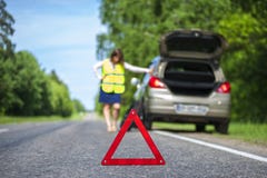 Женщина в отражательном жилете около сломленного автомобиля стоковое изображение Женщина в отражательном жилете около сломленного автомобиля стоковое изображение