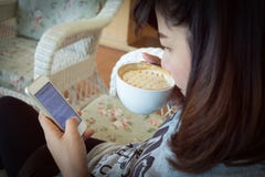 Женщина выпивая горячий кофе в кафе и использует мобильный телефон стоковые фото Женщина выпивая горячий кофе в кафе и использует мобильный телефон стоковые фото
