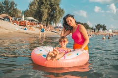 Женщина и ее плавание дочери на раздувном донуте стоковое фото Женщина и ее плавание дочери на раздувном донуте стоковое фото