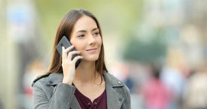 Женщина идя и вызывая по телефону в улице Женщина идя и вызывая по телефону в улице
