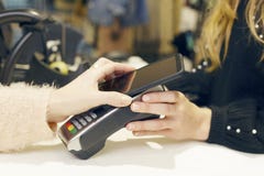 Женщина используя ее smartphone для того чтобы оплатить в магазине одежды Стоковые Фотографии RF Женщина используя ее smartphone для того чтобы оплатить в магазине одежды Стоковые Фотографии RF