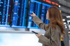 Женщина используя смартфон с доской данным по полета на аэропорте стоковые фото Женщина используя смартфон с доской данным по полета на аэропорте стоковые фото