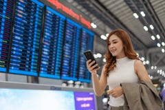 Женщина используя смартфон с доской данным по полета на аэропорте стоковые фото Женщина используя смартфон с доской данным по полета на аэропорте стоковые фото