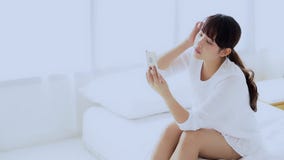 Женщина красивого портрета молодая азиатская сидя принимающ selfie с умным мобильным телефоном на спальне в утре дома Женщина красивого портрета молодая азиатская сидя принимающ selfie с умным мобильным телефоном на спальне в утре дома