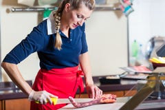 Женщина мясника режа часть мяса нервюры в ее магазине стоковые фотографии rf Женщина мясника режа часть мяса нервюры в ее магазине стоковые фотографии rf