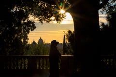 Женщина на балконе на заходе солнца с предпосылкой St Peter стоковая фотография Женщина на балконе на заходе солнца с предпосылкой St Peter стоковая фотография