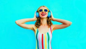 Женщина портрета счастливая усмехаясь слушая музыку в беспроводных наушниках на красочной сини стоковые изображения Женщина портрета счастливая усмехаясь слушая музыку в беспроводных наушниках на красочной сини стоковые изображения