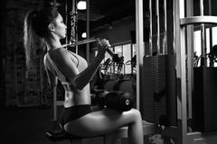Женщина работая назад на машине в спортзале стоковые фотографии rf Женщина работая назад на машине в спортзале стоковые фотографии rf